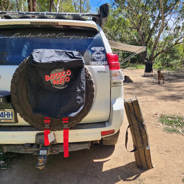 Bossco 4x4 Accessories Dirty Gear Bag installed on a rear wheel of white Toyota Landcruiser and a Bossco Camping Chair in box on side.